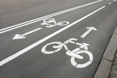 Photo of Two way bicycle lane with white signs on asphalt