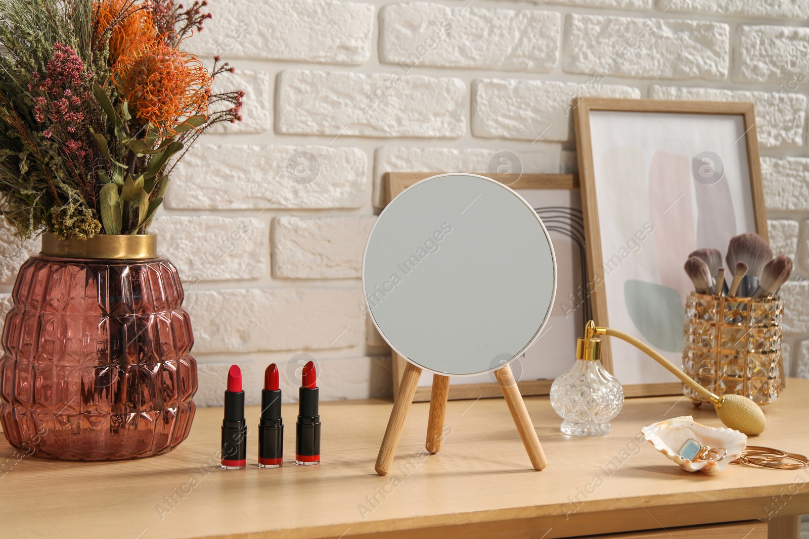 Photo of Mirror, makeup products, perfume and jewelry on wooden dressing table