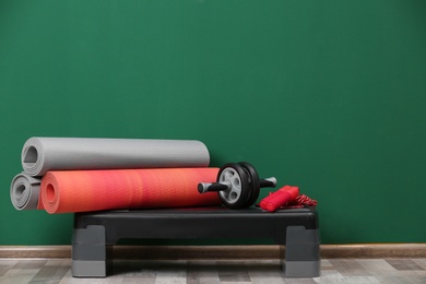 Set of fitness equipment on floor near color wall. Space for text