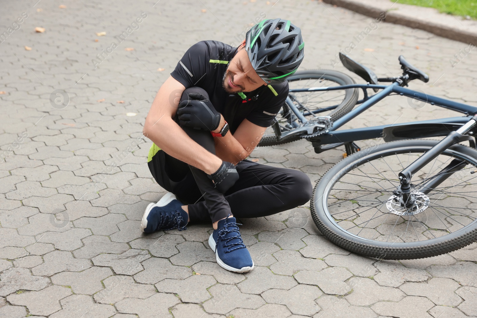 Photo of Man with injured knee near bicycle outdoors