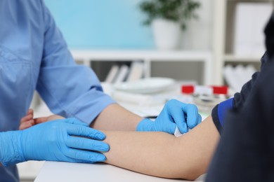 Photo of Laboratory testing. Doctor taking blood sample from patient at white table in hospital, closeup