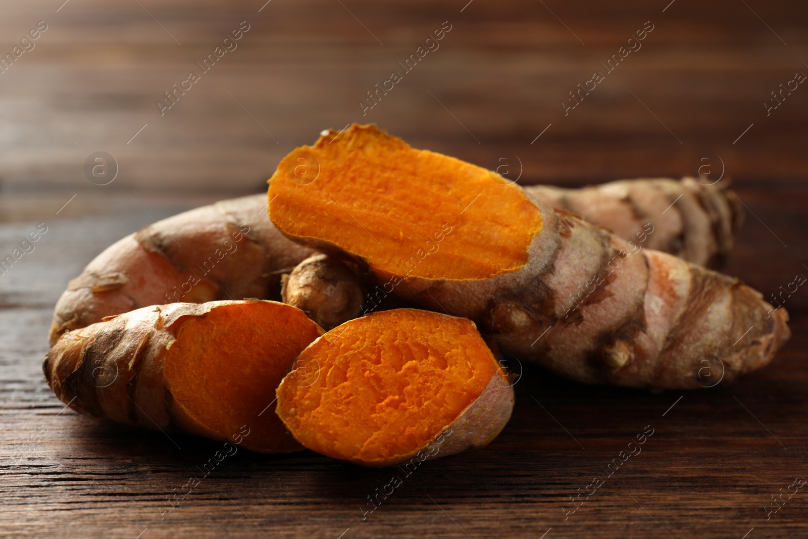 Photo of Fresh turmeric roots on wooden table, closeup