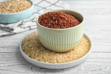 Kitchenware with different types of rice on wooden table