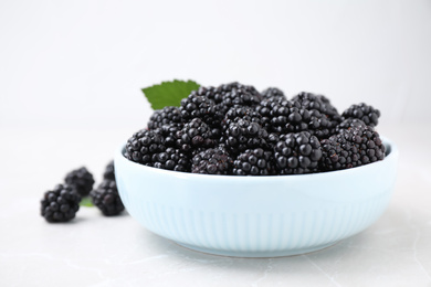 Fresh ripe blackberries in bowl on marble table, closeup