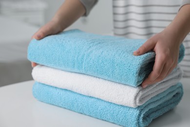 Woman touching soft light blue towel indoors, closeup