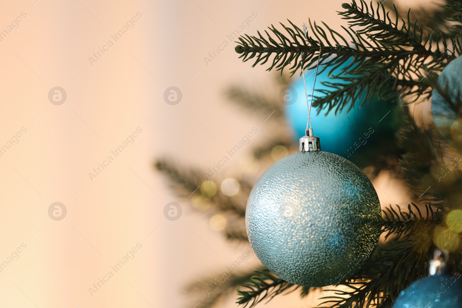 Photo of Christmas tree decorated with light blue festive balls on blurred background, closeup. Space for text