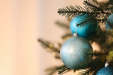 Photo of Christmas tree decorated with light blue festive balls on blurred background, closeup. Space for text