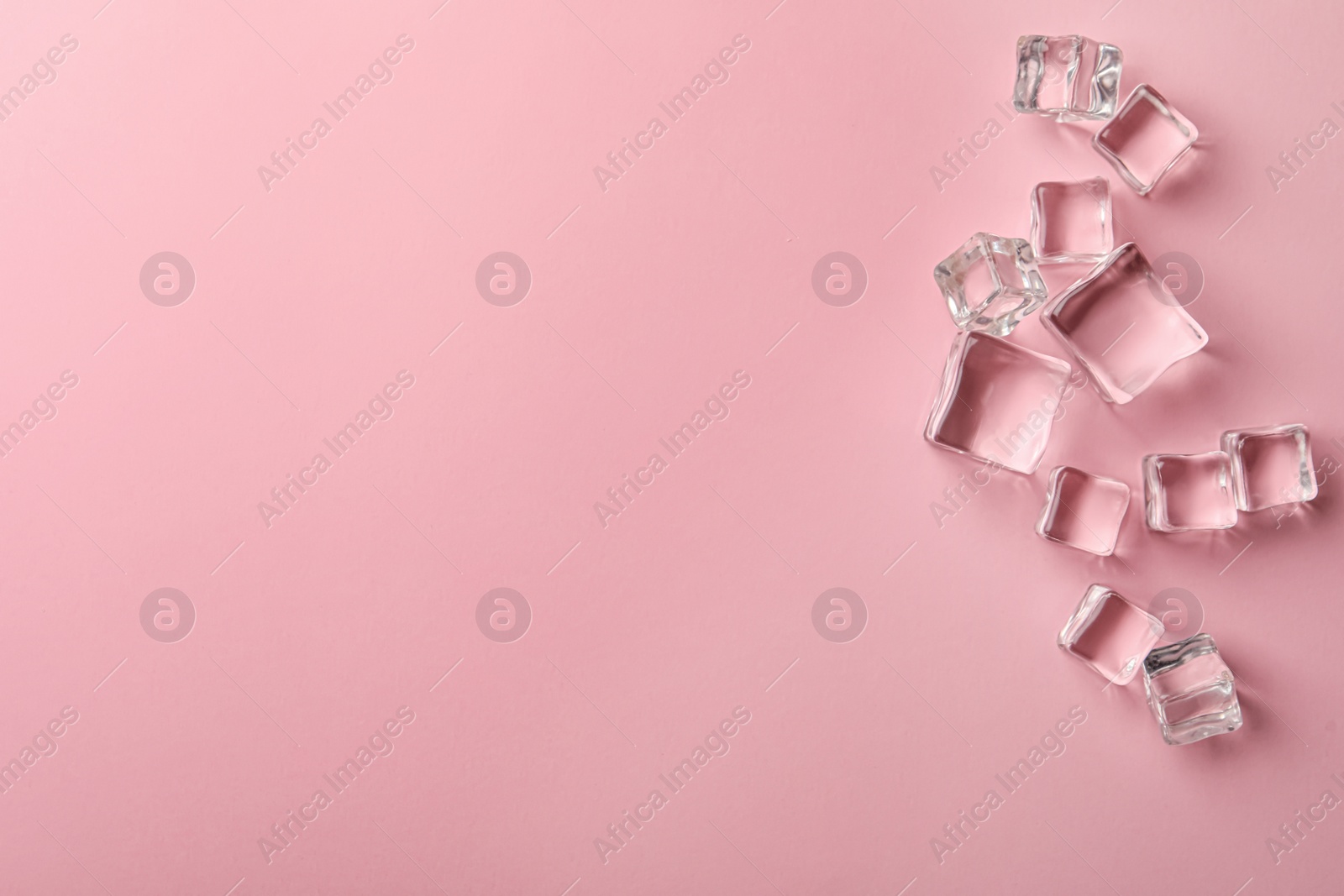 Photo of Crystal clear ice cubes on pink background, flat lay. Space for text