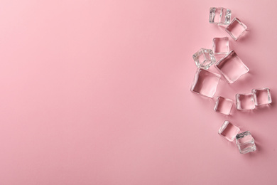 Photo of Crystal clear ice cubes on pink background, flat lay. Space for text