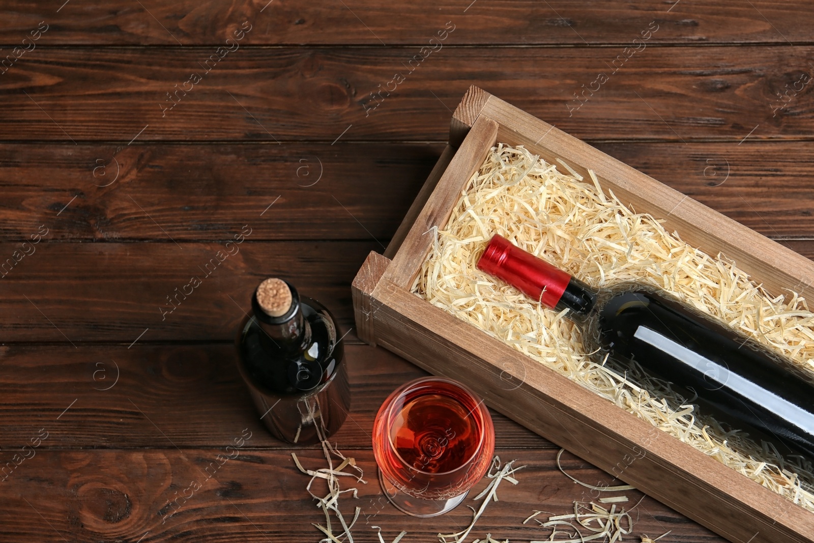 Photo of Composition with crate and bottles of wine on wooden table