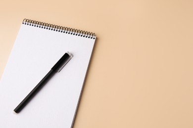 Notepad with erasable pen on beige background, top view. Space for text