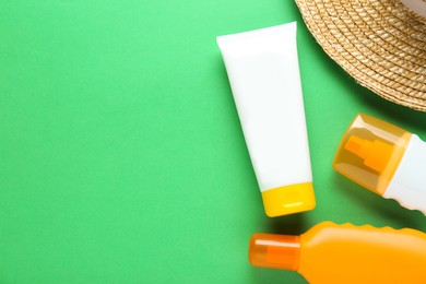 Photo of Suntan products and straw hat on green background, flat lay. Space for text