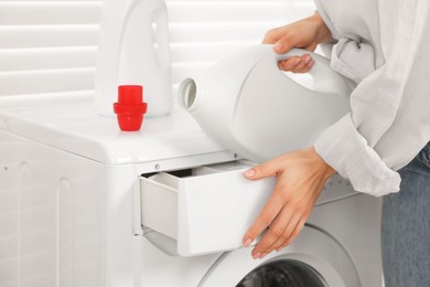 Photo of Woman pouring laundry detergent into washing machine indoors, closeup