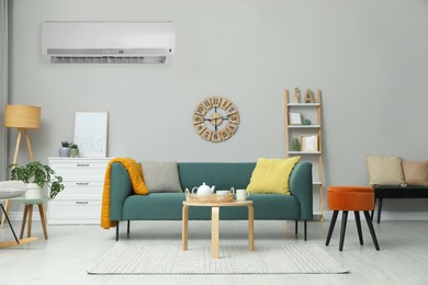 Image of Modern air conditioner on light wall in living room with stylish furniture