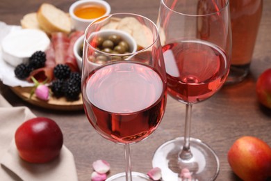 Delicious rose wine and snacks on wooden table, closeup