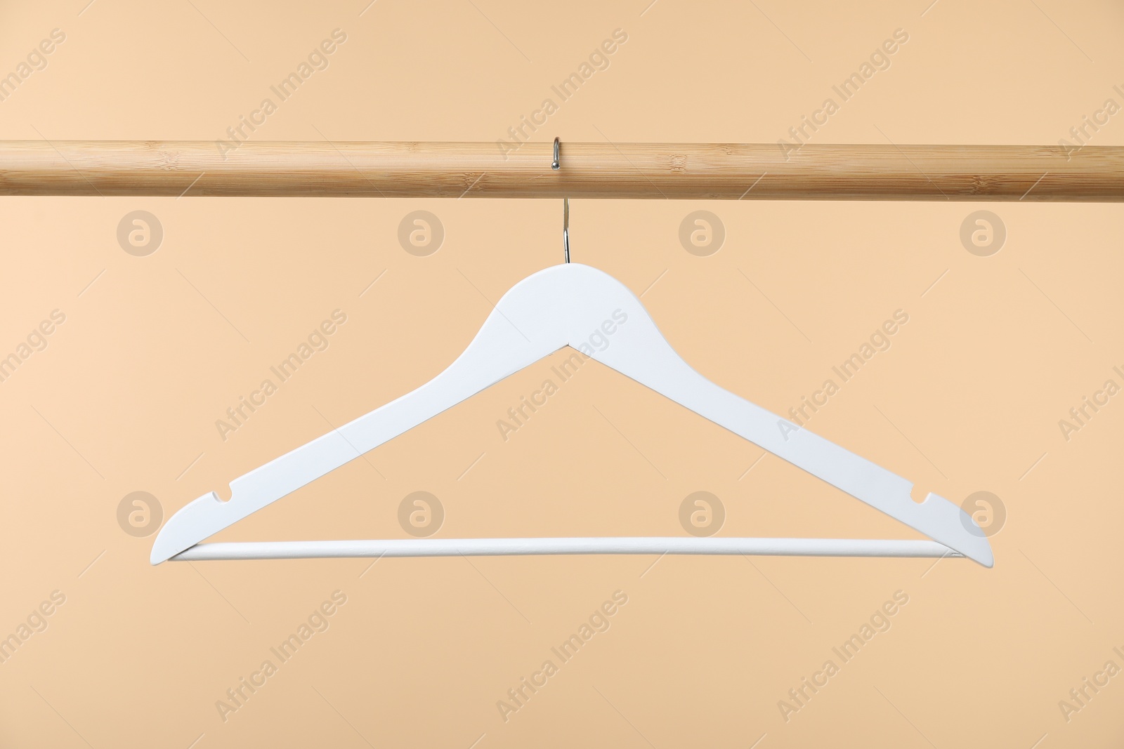 Photo of Empty clothes hanger on wooden rack against beige background