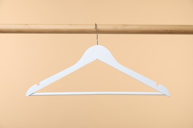 Photo of Empty clothes hanger on wooden rack against beige background