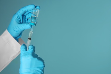 Doctor with syringe and medicine for vaccination on color background