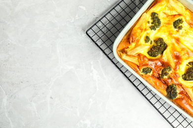 Photo of Tasty broccoli casserole in baking dish on cooling rack, top view. Space for text