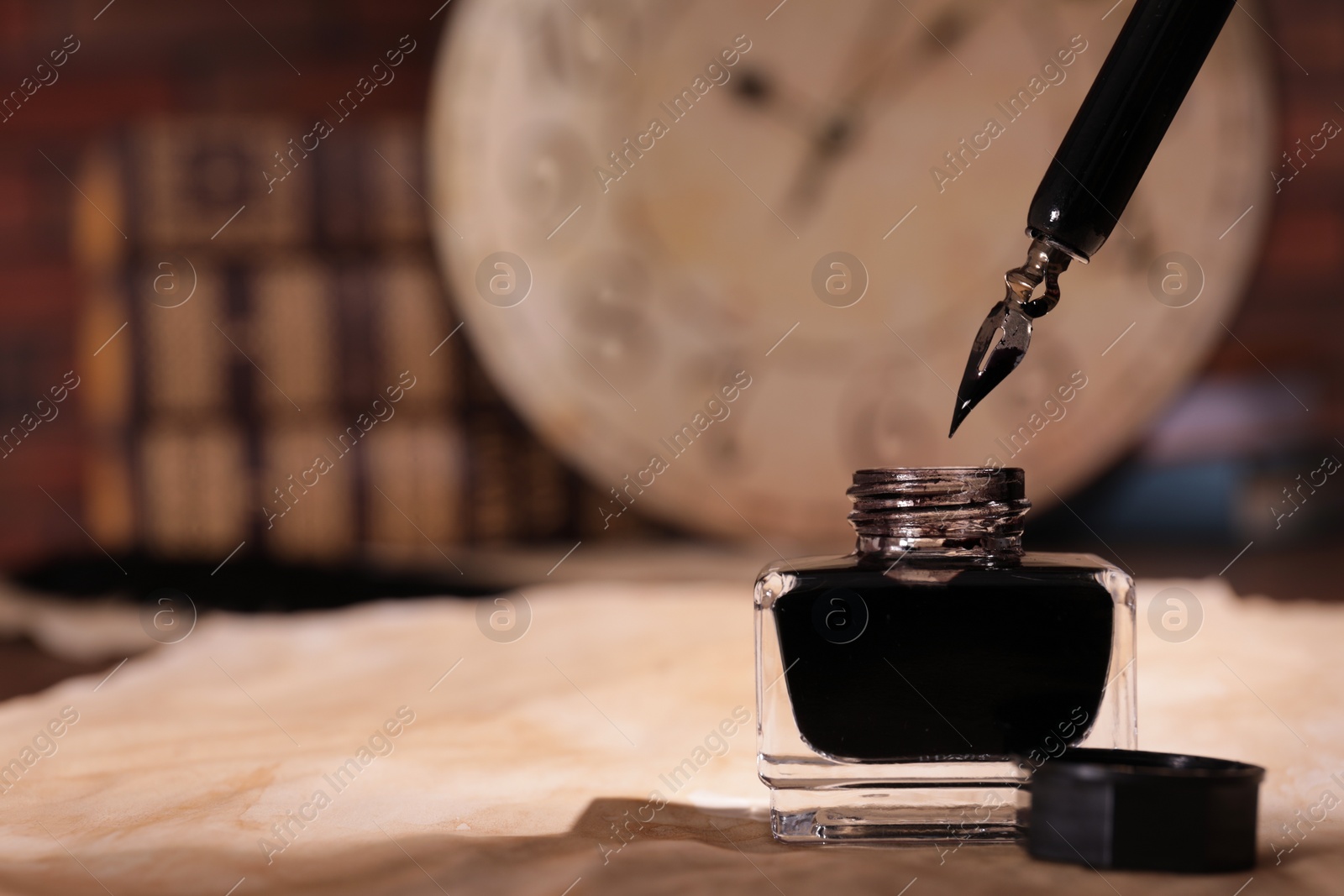 Photo of Inkwell, fountain pen and vintage parchment on table. Space for text