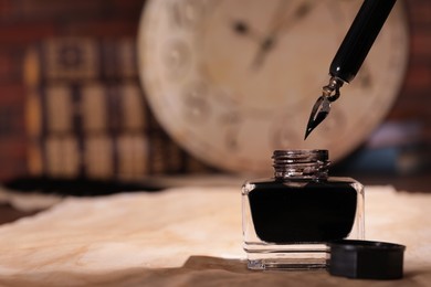 Photo of Inkwell, fountain pen and vintage parchment on table. Space for text