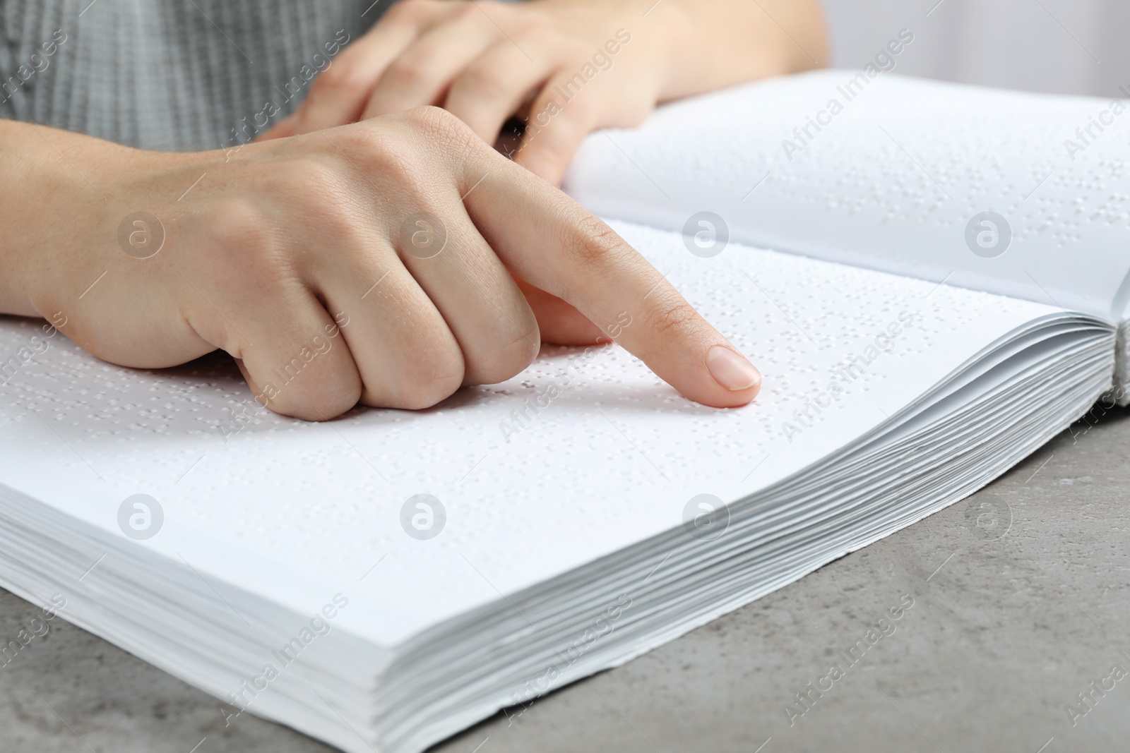 Photo of Blind person reading book written in Braille at table, closeup