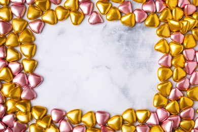 Frame made of heart shaped candies on white marble table, flat lay. Space for text