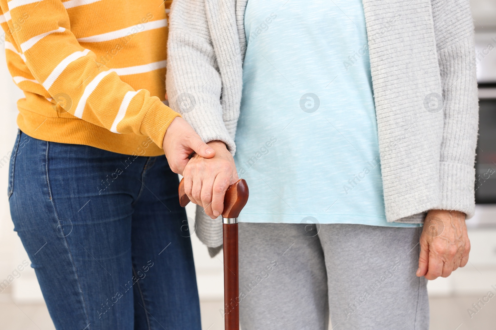 Photo of Elderly woman with walking cane and female caregiver, closeup view