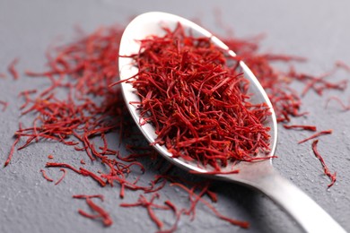 Photo of Aromatic saffron and spoon on gray table, closeup