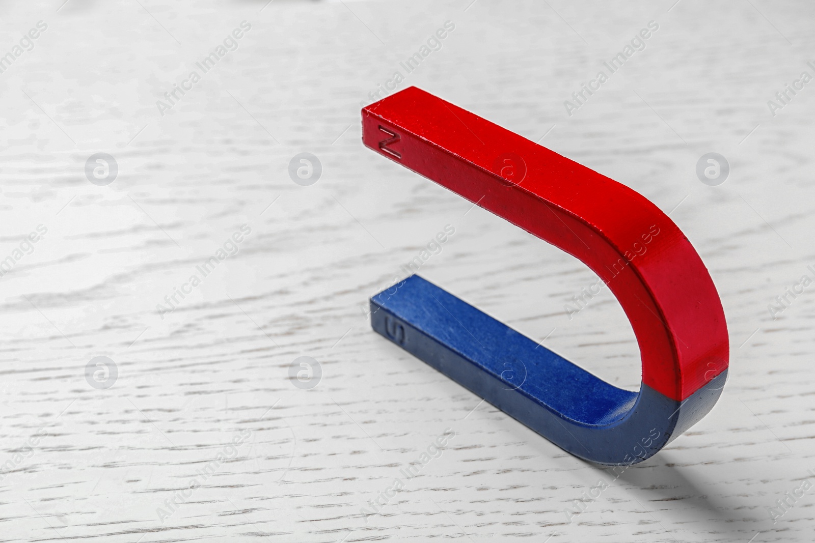 Photo of Red and blue horseshoe magnet on wooden background. Space for text