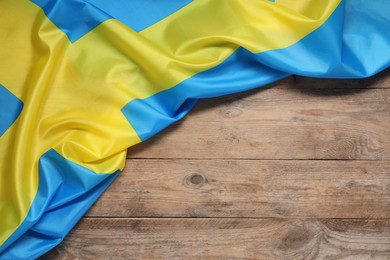 Photo of Flag of Sweden on wooden background, top view. Space for text