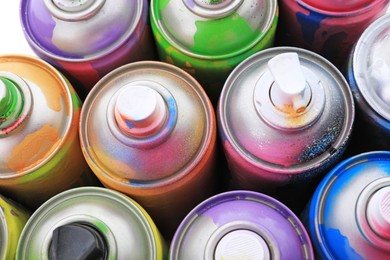 Photo of Used cans of spray paints as background, above view. Graffiti supplies