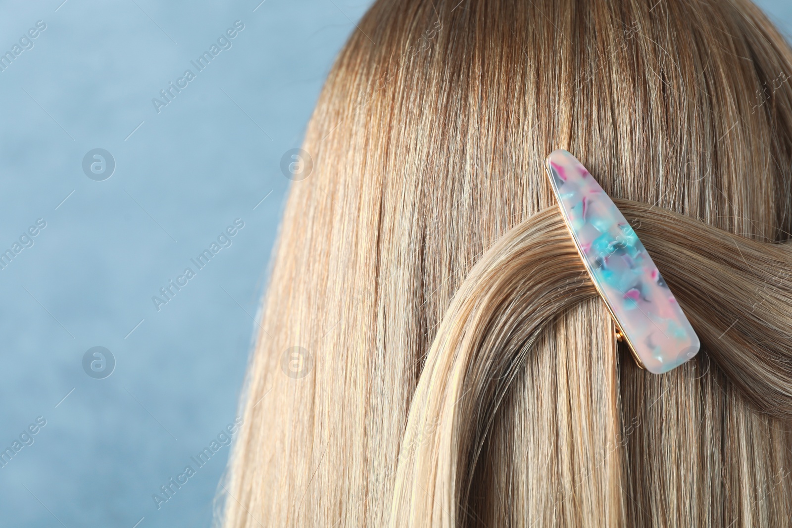 Photo of Young woman with beautiful hair clip on blue background, closeup