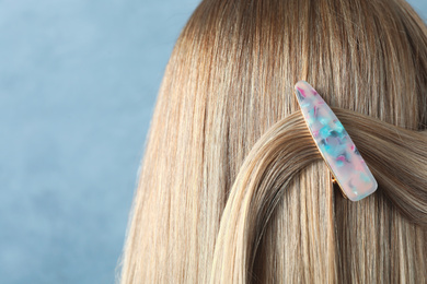 Photo of Young woman with beautiful hair clip on blue background, closeup