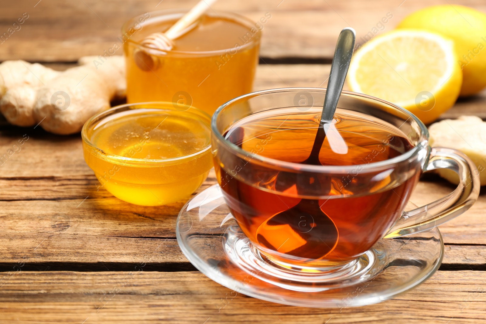 Photo of Tasty honey and tea on wooden table, closeup