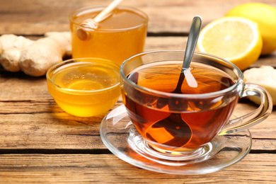 Photo of Tasty honey and tea on wooden table, closeup