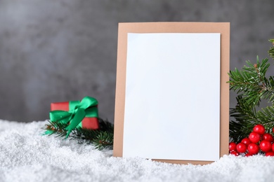 Blank Christmas card and festive decor on artificial snow, space for text