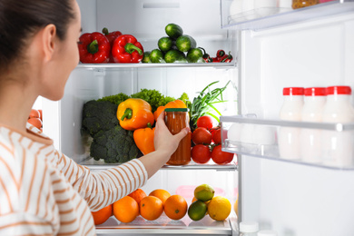 Photo of Young woman taking squash spread out of refrigerator, closeup
