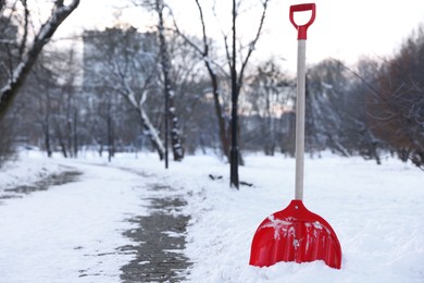 Photo of Snow shovel with wooden handle near sidewalk outdoors. Space for text