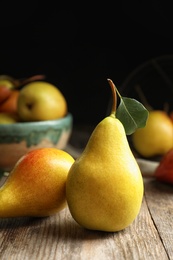 Photo of Ripe pears on wooden table against dark background