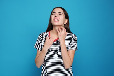 Photo of Young woman scratching neck on color background. Annoying itch