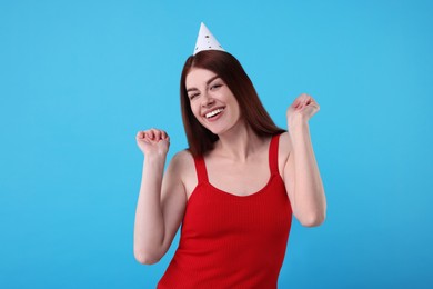 Photo of Happy woman in party hat on light blue background