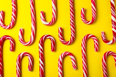 Photo of Sweet Christmas candy canes on yellow background, flat lay