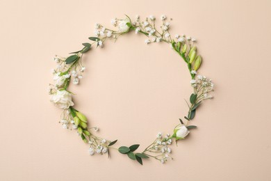 Frame made of beautiful gypsophila, roses, eucalyptus and freesia on beige background, top view. Space for text