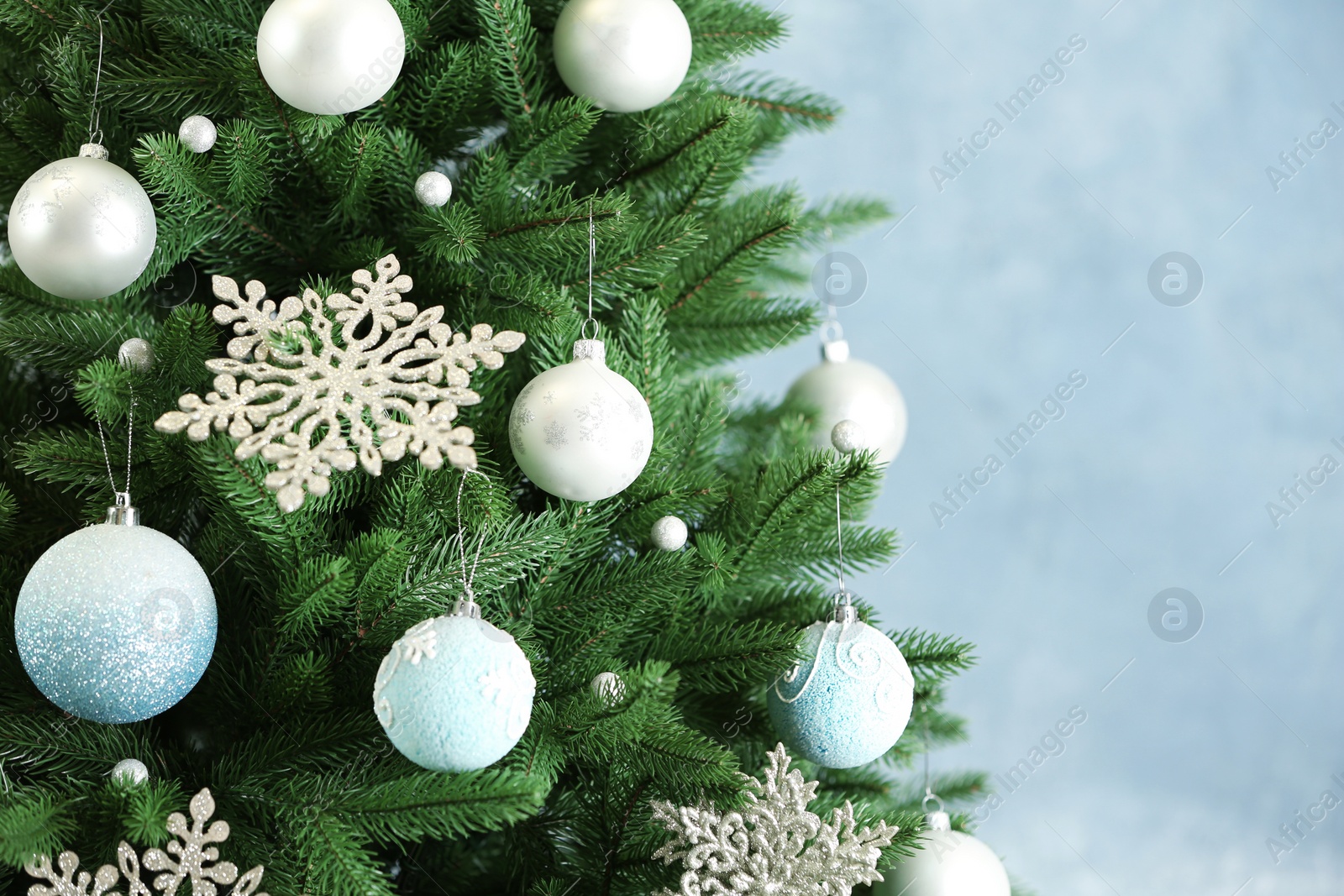 Photo of Beautiful Christmas tree with decor against light blue background. Space for text