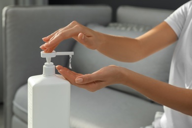 Photo of Woman applying hand sanitizer indoors, closeup. Personal hygiene during COVID-19 pandemic