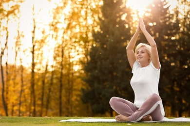 Photo of Happy mature woman practicing yoga in park. Active lifestyle