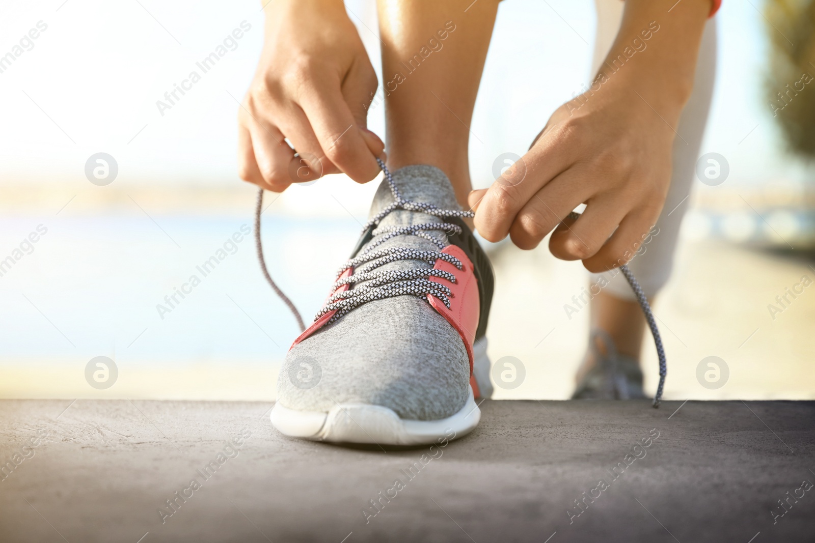 Image of Sporty woman tying shoelaces outdoors on sunny day, closeup