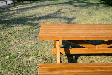 Photo of Empty wooden picnic table with bench in park on sunny day