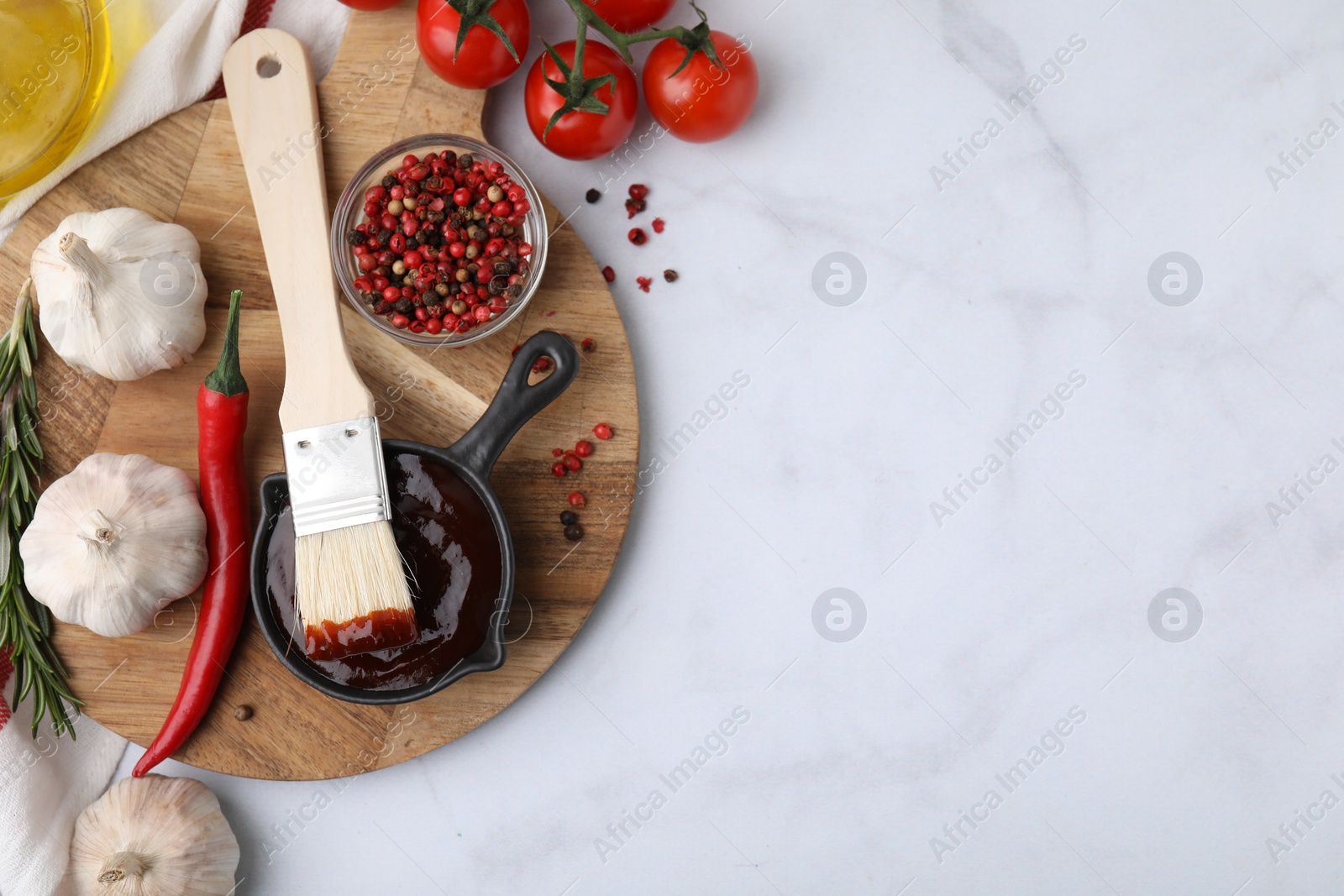 Photo of Marinade in gravy boat, ingredients and basting brush on white marble table, flat lay. Space for text